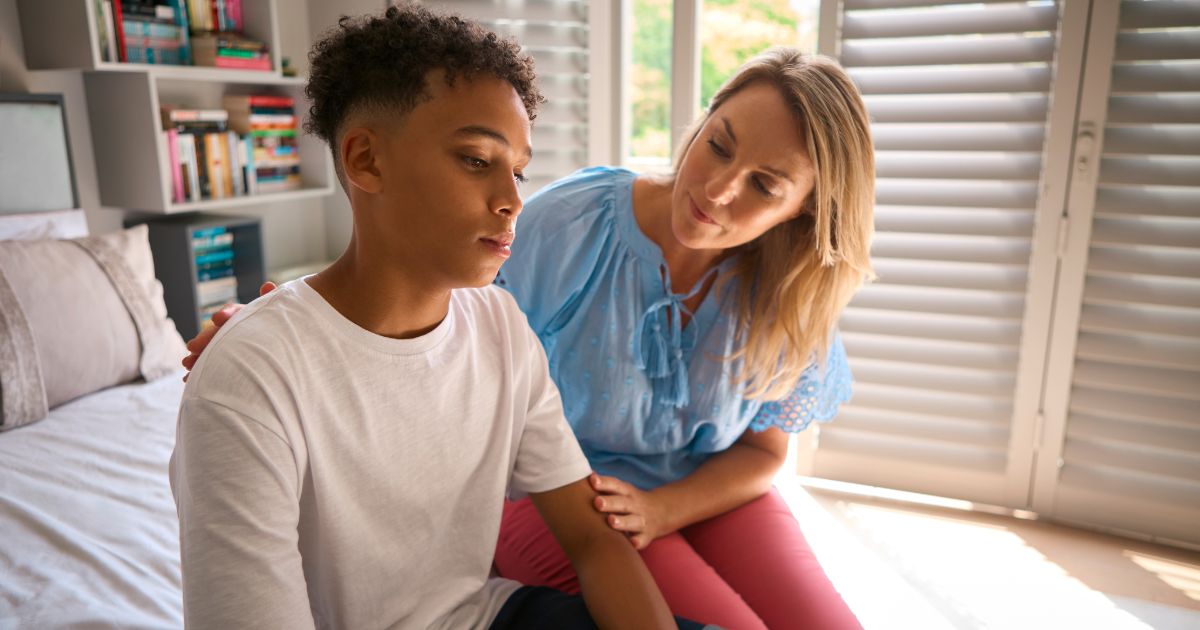Teenage boy being comforted by his mum