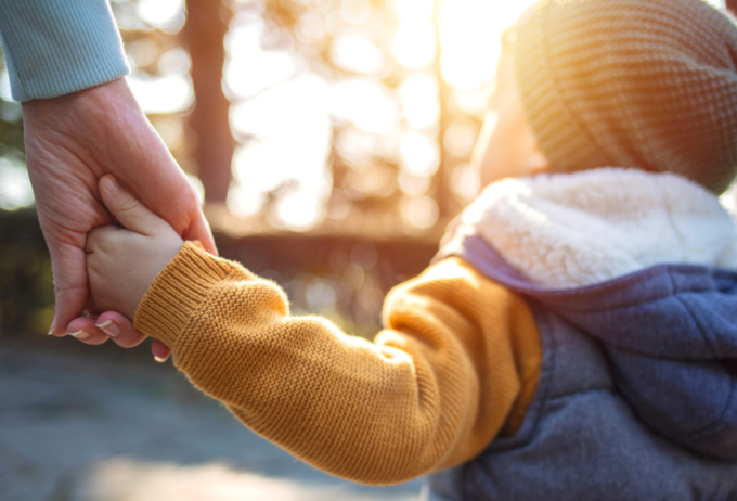 Child outdoors holding parent's hand